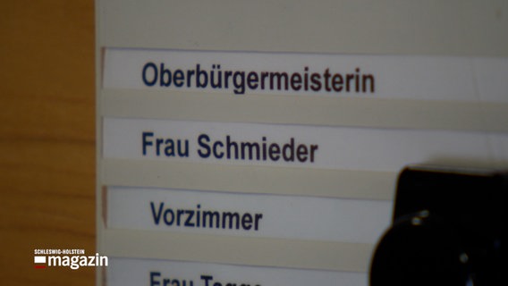 Auf einem Schild an einer Wand steht: Oberbürgermeisterin Frau Schmieder © NDR Foto: NDR Screenshot