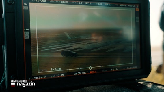 Auf einem Monitor wird das Bild einer Filmkamera gezeigt, welches ein Auto filmt. © NDR Foto: NDR BScreenshot