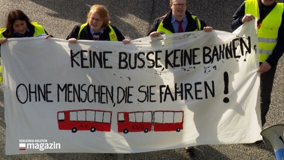 Menschen demonstrieren, dabei halten sie ein Banner hoch. Auf dem Banner steht: "Keine Busse, keine Bahnen, ohne Menschen, die sie fahren!" © NDR Foto: NDR Screenshot