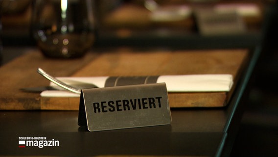 Auf einem Tisch steht ein Schild mit der Aufschrift "Reserviert" © NDR Foto: NDR Screenshot