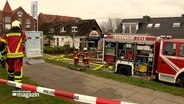 Feuerwehrfahrzeuge und EInsatzkräfte stehen vor einem abgebrannten Fischimbiss. © NDR Foto: NDR Screenshot