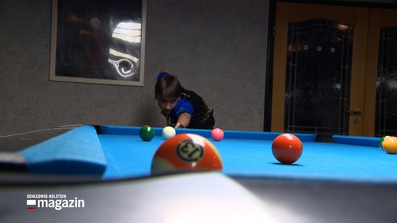 Ein Billardspieler setzt an einem blauen Billardtisch zum Stoß an. © NDR Foto: NDR Screenshot