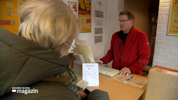 Ein Mann bedient eine Frau an einem Schalter eines Paketshops. © NDR Foto: NDR Screenshot