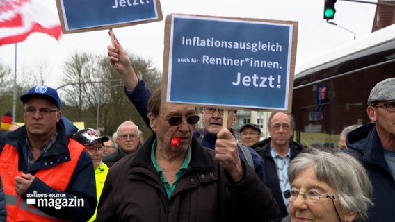 Ein Mann hält auf einer Demonstration ein Schild hoch, auf dem Schild steht: "Inflationsausgleich auch für Rentner*innen. Jetzt!" © NDR Foto: NDR Screenshot