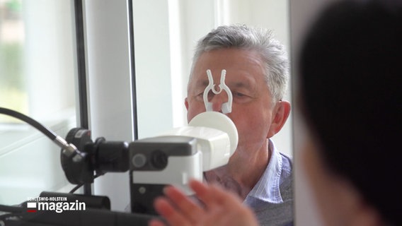 Ein Mann trägt eine Nasenklammer und bläst in ein Messgerät © NDR Foto: NDR Screenshot