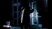 Nachgestellte Einbruchszene: Eine Person leuchtet mit einer Taschenlampe durch das Fenster eines Hauses © NDR Screenshot 