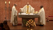 Drei katholische Pfarrer stehen bei einer Profanierung in einer Kirche © NDR Screenshot 