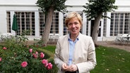 Ulrike-Wolff Thomsen steht in einem Vorgarten und lächelt in die Kamera. © NDR Foto: Svenja Lanz