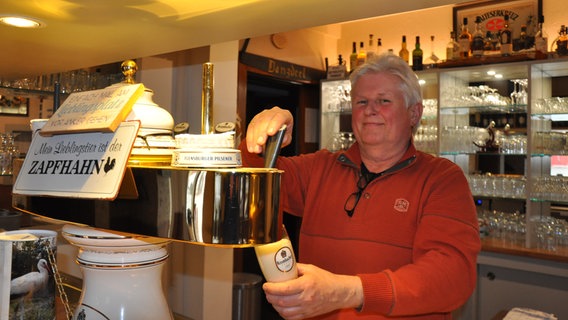 Ein Mann steht hinter dem Tresen eines Landgasthofs und zapft ein Bier. © NDR Foto: Peter Bartelt