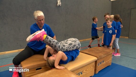 Kinder machen Turnübungen in einer Sporthalle. © NDR 