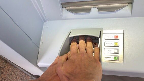 Eine Person verdeckt mit einer Hand die andere bei der Eingabe der Kartenpinnummer an einem Geldautomaten. © NDR Foto: Julia Jänisch