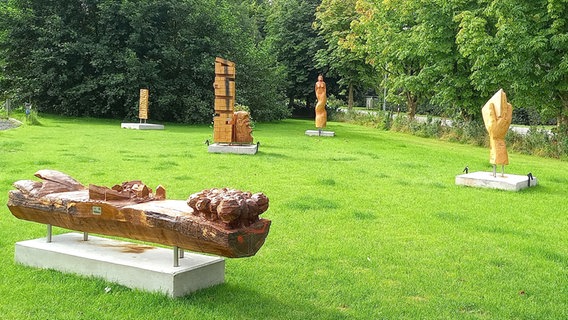 Skulpturen aus Holz stehen in einem Garten. © Yoli A. Manowski Foto: Yoli A. Manowski