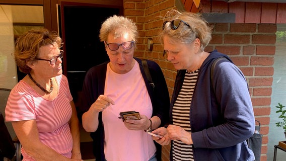 Drei ältere Damen blicken auf ein Handy. © NDR Foto: Lena Haamann