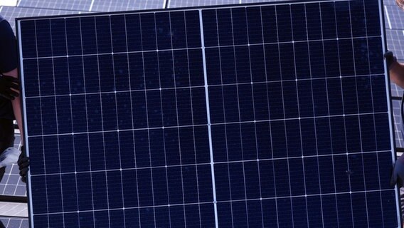 Monteure tragen ein Solarmodul auf dem Dach eines Gebäudes. © picture alliance/dpa | Waltraud Grubitzsch Foto: Waltraud Grubitzsch