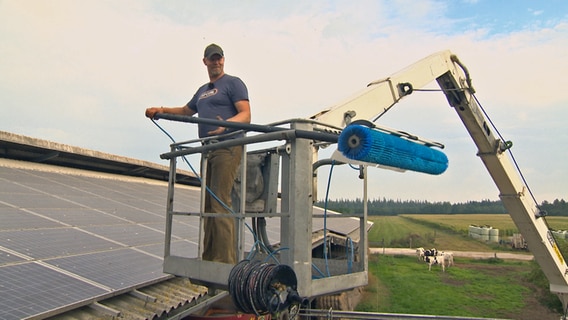 Solaranlagenreiniger Björn Matthiesen aus Niebüll steht im Korb seines Gerüstwagen und hält ein spezielles Reinigungswerkzeug in den Händen. © NDR 