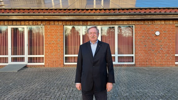 Holger Bajorat, Bürgermeister von Stolpe, steht vor dem Gemeinschaftshaus des Ortes mit einer Solaranlage auf dem Dach. © NDR Info Foto: Arne Schulz