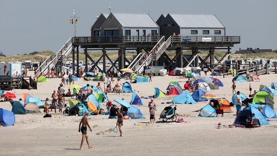 Zahlreiche Besucher liegen mit Zelten und Strandmuscheln am Strand von St. Peter-Ording. © dpa Foto: Bodo Marks