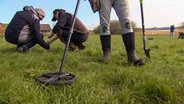 Ein Mann sucht mit einem Metalldetektor nach Wertvollem in der Erde. © NDR 