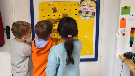 Grundschüler der Grundschule Nordost in Schwarzenbek kleben Kärtchen mit Silben auf ein Plakat. © NDR Foto: Anne Passow
