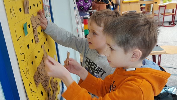 Grundschüler der Grundschule Nordost in Schwarzenbek kleben Kärtchen mit Silben auf ein Plakat. © NDR Foto: Anne Passow