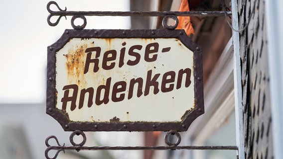 Ein Schild mit der Aufschrift "Reise-Andenken". © imago images / Zoonar 