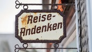 Ein Schild mit der Aufschrift "Reise-Andenken". © imago images / Zoonar 
