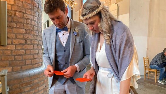 Ein Hochzeitpaar hält rote Papierherzen in den Händen in der Kirche Flensburg © NDR Foto: Lisa Knittel