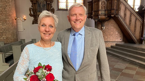 Ein Hochzeitspaar lächelt in einer Kirche in die Kamera © NDR Foto: Lisa Knittel