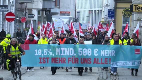 Mitglieder der Gewerkschaft verdi tragen ein Banner und Flaggen beim Streik in der Lübecker Innenstadt © NDR 