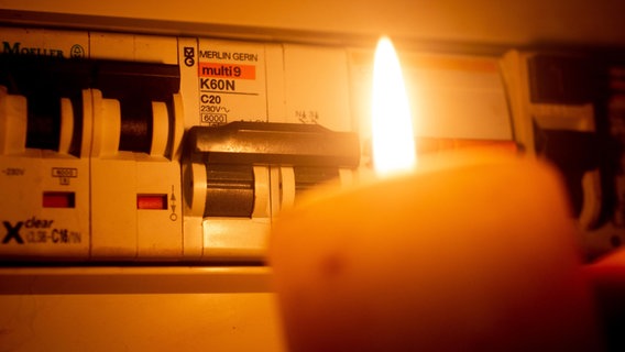 Eine Kerze scheint vor einem Sicherungskasten © picture alliance / CHROMORANGE | Andreas Poertner Foto: Andreas Poertner