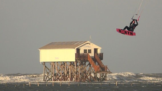 Bei stürmischen Wetter fliegt eine Kitesurfer in St. Peter-Ording über die Wellen © dpa - Bildfunk Foto: Daniel Friedrichs