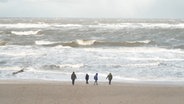 Spaziergänger gehen am Strand von Sylt während eines Sturms. © NDR 