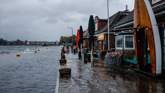 Die Straße vor den Cafés und Geschäften am Tiessenkai im Kieler Stadtteil Holtenau ist vollständig von der Ostsee überflutet. © dpa-Bildfunk Foto: Axel Heimken
