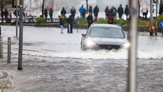Ein Auto bahnt sich in Flensburg einen Weg durch eine überflutete Straße. © dpa-Bildfunk Foto: Frank Molter