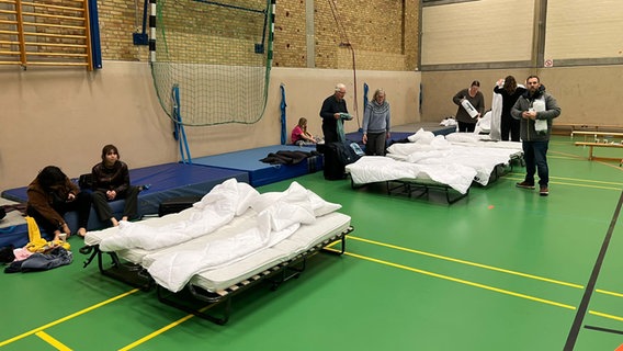 Mehrere Personen stehe in einer Notunterkunft in einer Turnhalle. © Rainer Haulsen/stellv. Bürgermeister Schleswig Foto: Rainer Haulsen