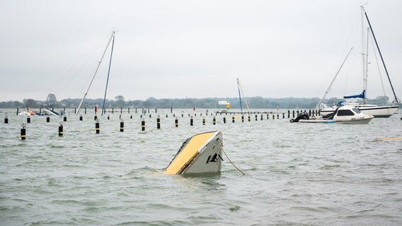 Nur noch die Spitze eines gesunkenen Schiffes schaut im Hafen nach einer Sturmflut aus dem Wasser. © picture alliance Foto: Daniel Bockwoldt