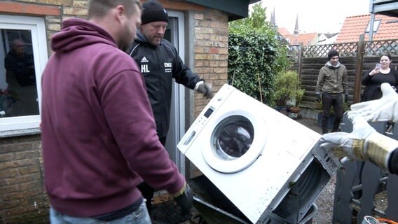 Schleswig: Drei Männer transportieren eine Waschmaschine. © TNN 