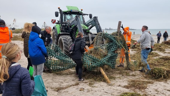 Mehrere Helfer und ein traktor helfen bei den Aufräumaktionen nach der Sturmflut in Grömitz © NDR Foto: Julian Marxen