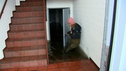 Eine Frau blickt in einen überschwemmten Keller in Flensburg. © NDR 