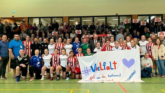 Team, Betreuer und Fans des SV Sülfeld in einer Sporthalle. Das Team hält ein Spruchband mit der Aufschrift: Vielfalt.  