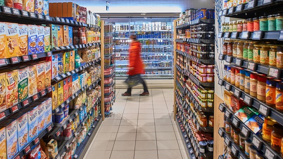 Eine Frau geht zwischen Supermarkt-Regalen entlang. © picture alliance Foto: Carsten Milbret