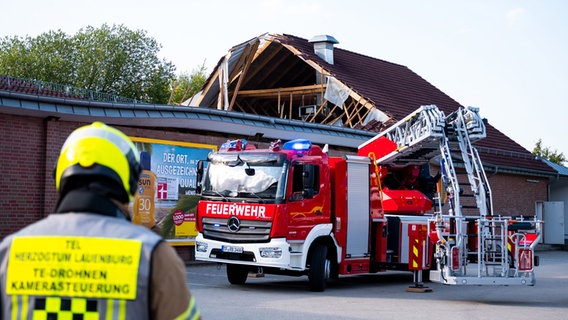 In Ratzeburg steht die Feuer·wehr vor dem teil·weise eingestürzten Dach von einem Supermarkt. © dpa Foto: Daniel Bockwoldt