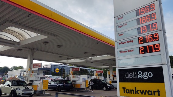 Die Preistafel einer Tankstelle, stehende Autos an Zapfsäulen im Hintergrund © NDR Foto: Peer-Axel Kroeske