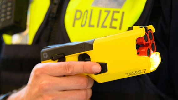 Ein Polizeibeamter hält im Rahmen der Pressekonferenz einen Taser 7 in der Hand. © picture alliance/dpa/dpa-Zentralbild Foto: Soeren Stache