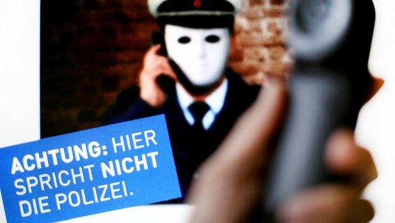 Ein Telefonhörer ist vor einem Plakat der Polizei mit der Aufschrift "Achtung: Hier spricht nicht die Polizei" zu sehen. © dpa-Bildfunk Foto: Martin Gerten