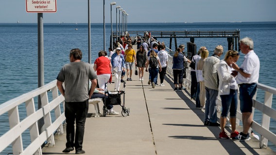Touristen laufen an der Ostsee am Timmendorfer Strand über die Seebrücke. © dpa-Bildfunk Foto: Axel Heimken