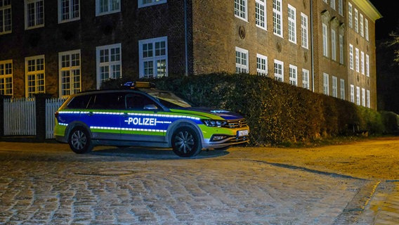 Ein Polizeiauto steht vor einem Gebäude in Flensburg.  Foto: Karsten Sörensen