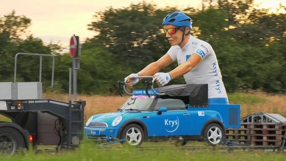 Ein blaues Werbefahrzeug mit einer großen Tour de France-Figur wird auf einem Anhänger transportiert. © Westküsten-News Foto: Sebastian Iwersen