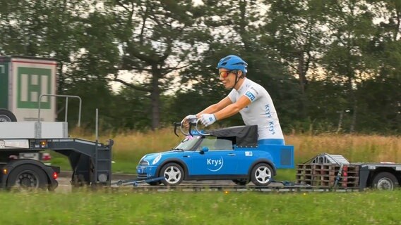 Ein blaues Werbefahrzeug mit einer großen Tour de France-Figur wird auf einem Anhänger transportiert. © Westküsten-News Foto: Sebastian Iwersen