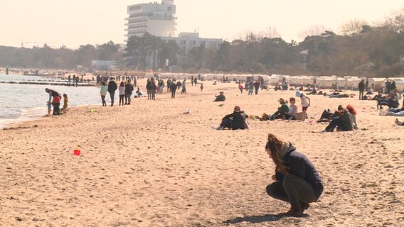 Menschen sitzen am Strand und genießen das Wetter.  